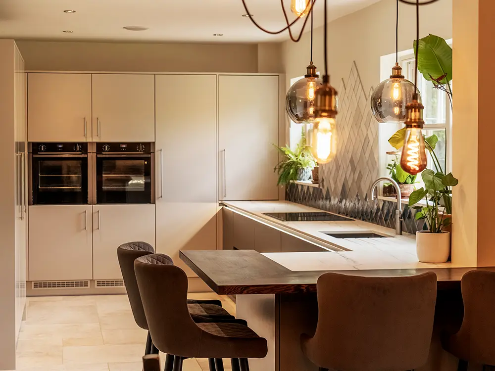 Modern handleless kitchen with warm lighting and oak breakfast bar in Harrogate