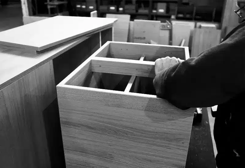 Craftsman assembling a solid wood cabinet frame by hand inside the DKD workshop.