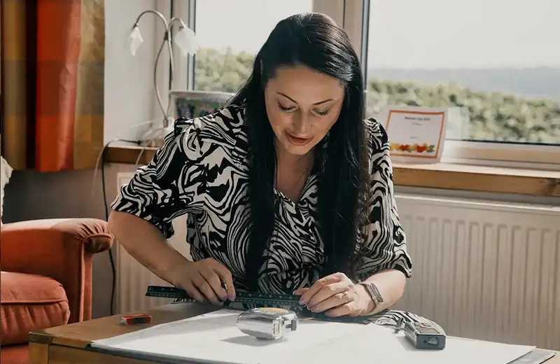 Kitchen designer measuring up plans at a client’s home during a design consultation.