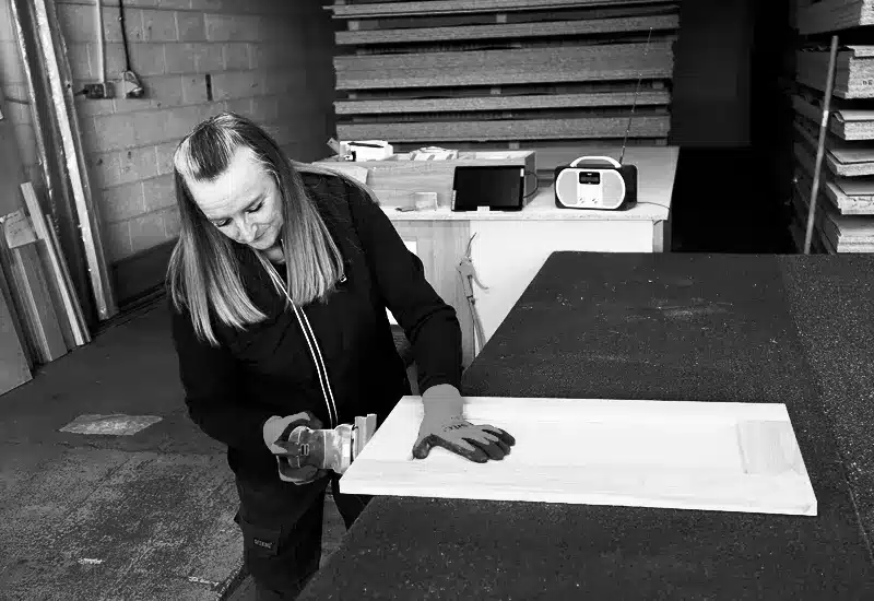 Craftswoman hand-finishing a timber cabinet door in the Designer Kitchen Direct workshop.