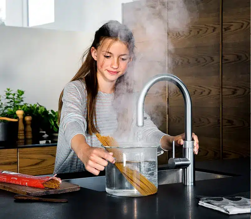 Modern boiling water tap being used to fill a pan in a contemporary kitchen