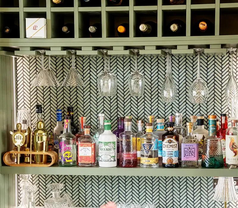 Bespoke painted drinks cabinet with wine rack, hanging glass storage and decorative tiled splashback