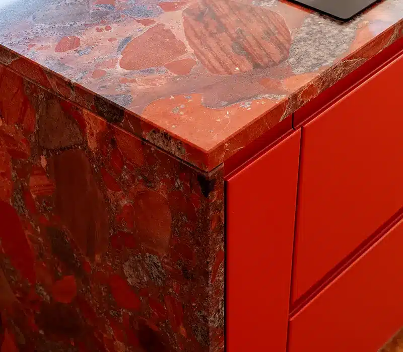 Statement red stone worktop with bold natural patterning and bespoke red cabinetry