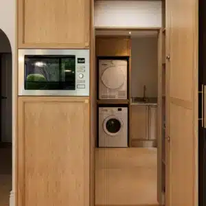Bespoke concealed utility entrance integrated into full-height oak kitchen cabinetry