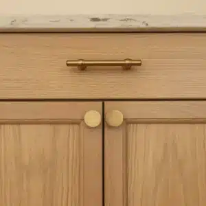Close-up of stained oak kitchen cabinetry with brushed brass knobs and drawer handle
