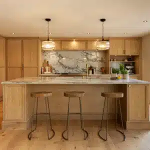 Bespoke stained oak kitchen with large island, brass tap and three bar stools